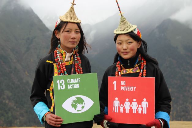 Two people holding SDG signs